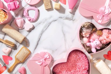 Pembe renkli kalp şekilli hediye kutularının üst görüntüsü ev yapımı banyo malzemeleri, lokum ve beyaz mermer arka plandaki kadınlar için vücut bakım ürünleri. Noel hediyeleri kavramı.