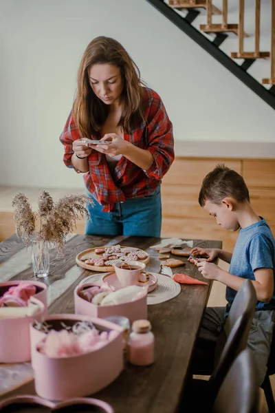 소년은 어머니에게 선물을 준비하고 쿠키를 분홍색 아이싱을 모양으로 — 스톡 사진
