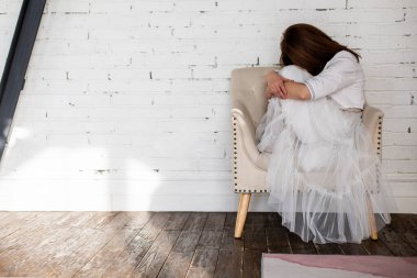 Etek etekli üzgün kadın, beyaz çatı katındaki koltukta oturmaktan endişeleniyor. Mutsuz, zarif bir kadın stres depresyonuna giriyor ya yalnız ya da kötü haberler alıyor. Üzgün, modaya uygun bayan.