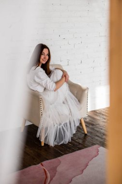 Etek etekli üzgün kadın, beyaz çatı katındaki koltukta oturmaktan endişeleniyor. Mutsuz, zarif bir kadın stres depresyonuna giriyor ya yalnız ya da kötü haberler alıyor. Üzgün, modaya uygun bayan.