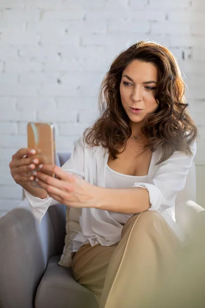 Glückliche Modische Frau Sitzt Auf Sessel Posiert Selfie Mit Smartphone — Stockfoto