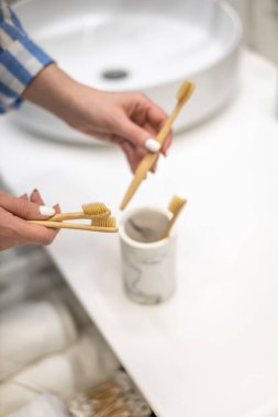 Çekmecede çevre banyosu düzenleyen ve bambu diş fırçalarını bir fincana koyan kadınların en iyi görüntüsü. Sıfır atık ve daha az plastik konsept kullanımı. Çevre dostu biyolojik çözünebilir diş fırçası..