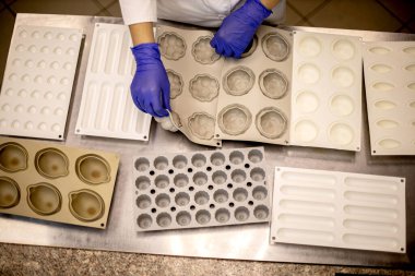 Pasta pişirmek için elinde bir yığın plastik küf tepsisi tutan güzel kadın şefin portresi olumlu duygulara sahip. Mutfak malzemeleriyle poz veren mutlu esmer pastacı.