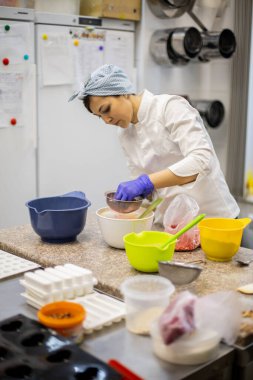 Kendine güvenen mutfak çalışanı kadın kremalı çikolatalı tart süslemek için elek aracılığıyla çilek tozu sürüyor. Meşgul kadın aşçı aşçılıkta pasta için lezzetli dekorlar pişiriyor.