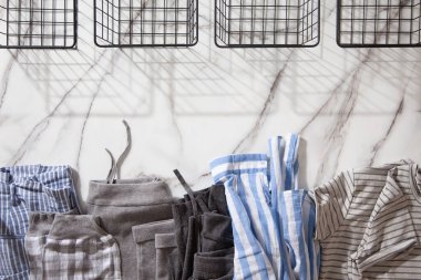 Beyaz mermer masaya konmuş organik pamuklu pijama grubu katlanıp beyaz çelik tel örgü sepetlere yerleştirilmeye hazır. Dolap düzenleme konsepti. İskandinav tarzı renkler. Konmari yöntemi kullanılıyor.
