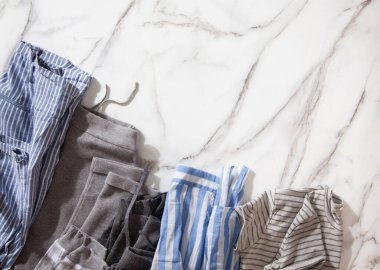 Beyaz mermer masaya konmuş organik pamuklu pijama grubu katlanıp beyaz çelik tel örgü sepetlere yerleştirilmeye hazır. Dolap düzenleme konsepti. İskandinav tarzı renkler. Konmari yöntemi kullanılıyor.