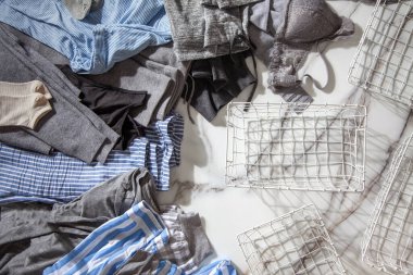 Beyaz mermer masaya konmuş organik pamuklu pijama grubu katlanıp beyaz çelik tel örgü sepetlere yerleştirilmeye hazır. Dolap düzenleme konsepti. İskandinav tarzı renkler. Konmari yöntemi kullanılıyor.