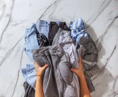 Kadın elleri temizlik için temiz giysiler yığıyor ve beyaz mermer masanın üzerine çelik tel dolap sepetleri düzenliyor. Marie Kondo tarzı ve yer tasarrufu depolama kavramı.