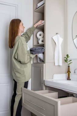 Kadınların elleri banyodaki organik pamuktan yapılan temiz beyaz havluları düzgünce yerleştiriyor ya da sergiliyor. KonMari yöntemiyle banyo çarşaf dolabı ve havlu deposu düzenleme kavramı