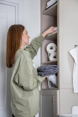 Kadınların elleri banyodaki organik pamuktan yapılan temiz beyaz havluları düzgünce yerleştiriyor ya da sergiliyor. KonMari yöntemiyle banyo çarşaf dolabı ve havlu deposu düzenleme kavramı