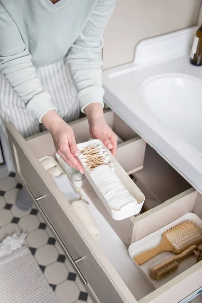 主婦の手は 洗面台の下の引き出しにタオルを巻き上げました 浴室の上の眺めの記憶空間を組織する女性 家庭で家事を掃除する女性 近代的な近藤真里枝の保存方法 — ストック写真