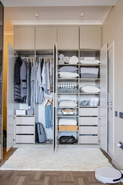 Wardrobe with perfect order clothes in blue and light shades on the hangers and things in containers. The concept of organizers and cleanliness in the hous