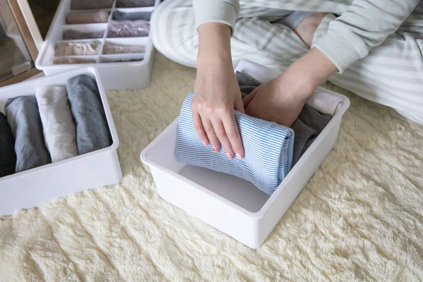 İç çamaşırı ve tişört depolarını düzenleyen kadın eller Marie Kondo 'nun yöntemini kullanır. Kusursuz ev hanımı gardırop organizatörlerine kıyafet yerleştiriyor. Giyim düzenleme çözümleri düzgünce ayarlanıyor