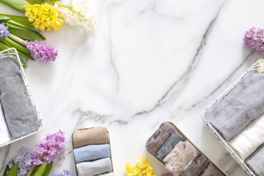 Mari Kondo 'nun doğal çiçeklerle süslenmiş iç çamaşırı organizasyonu. Üst görünüm çağdaş katlanmış konteynır kılıfları mermer zeminde giysi. Güzel gardırop.