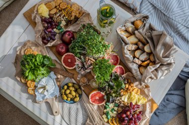 Üst kattaki konforlu oda servis masasının etrafı rahat yastıklarla çevrili ve parti kutlaması için hazır. Sağlıklı, taze, lezzetli yemek ve içecek rahat oturma odası hygge boho scandi dekoru.