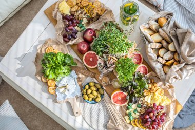 Üst kattaki konforlu oda servis masasının etrafı rahat yastıklarla çevrili ve parti kutlaması için hazır. Sağlıklı, taze, lezzetli yemek ve içecek rahat oturma odası hygge boho scandi dekoru.