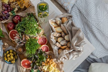 Üst kattaki konforlu oda servis masasının etrafı rahat yastıklarla çevrili ve parti kutlaması için hazır. Sağlıklı, taze, lezzetli yemek ve içecek rahat oturma odası hygge boho scandi dekoru.