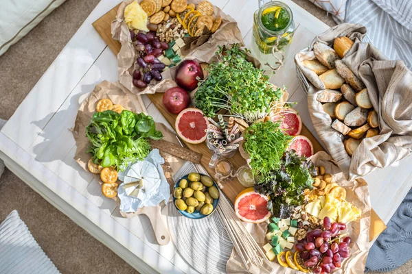 Üst kattaki konforlu oda servis masasının etrafı rahat yastıklarla çevrili ve parti kutlaması için hazır. Sağlıklı, taze, lezzetli yemek ve içecek rahat oturma odası hygge boho scandi dekoru.