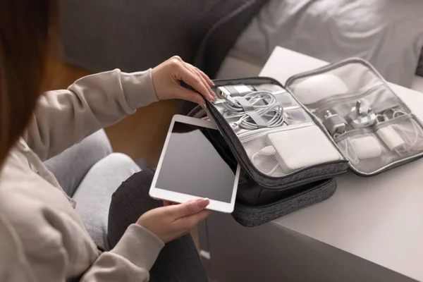 Female hands putting tablet pc into comfortable bag storage get ready to business trip or vacation