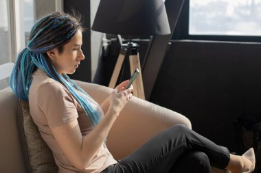 Kendine güvenen hippi kadın internette sohbet ediyor. Akıllı telefon kullanarak mesaj yazma mobil uygulaması kullanıyor.