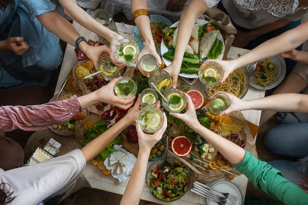 Top vista closeup amigos do sexo feminino mãos brinda brindar copo de bebida saudável sobre servindo mesa — Fotografia de Stock