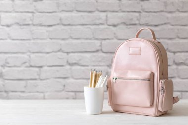 Beyaz çatı katında masa başında kırtasiye malzemeleriyle dolu bir kız okul çantası. Okul konseptine dönelim.