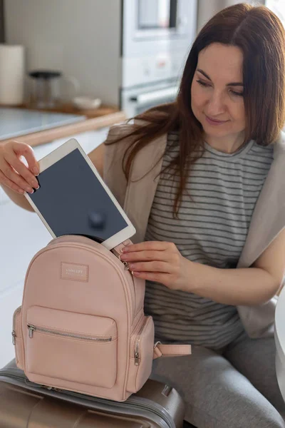 As mãos femininas colocando tablet pc em armazenamento confortável saco prepare-se para viagem de negócios ou férias — Fotografia de Stock