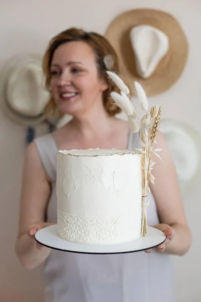 Gelukkig elegante vrouw poseren met smakelijke verse taart crème beige ingericht in boho scandi stijl — Stockfoto