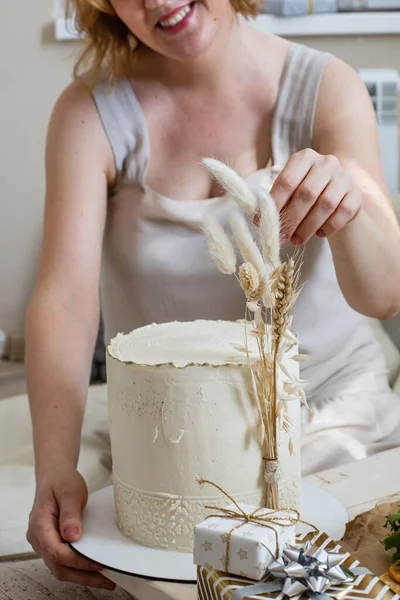 Gelukkig elegante vrouw poseren met smakelijke verse taart crème beige ingericht in boho scandi stijl — Stockfoto