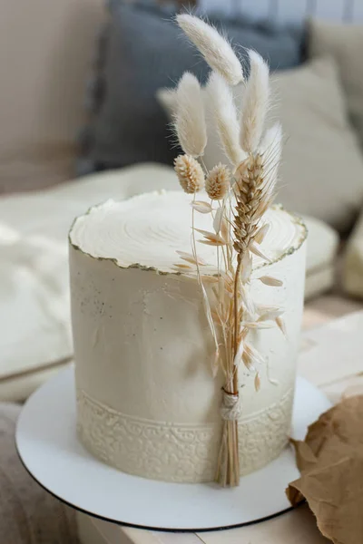 Verbazingwekkende minimalistische taart crème beige versierd door droog oor van tarwe katoen in boho scandi stijl — Stockfoto
