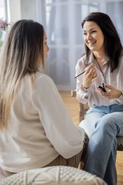 Makyaj sanatçısı, güzellik salonunda çalışan makyaj fırçasına makyaj malzemesi uyguluyor.