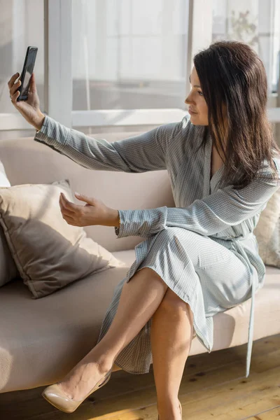 Junge Frau mit Brille macht Selfie-Foto auf Smartphone, während sie im Café sitzt — Stockfoto