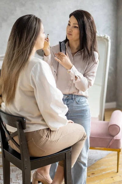 Profesionální ženské make-up umělec použití kosmetiky na modelu obličeje použití štětce práce v salonu krásy — Stock fotografie