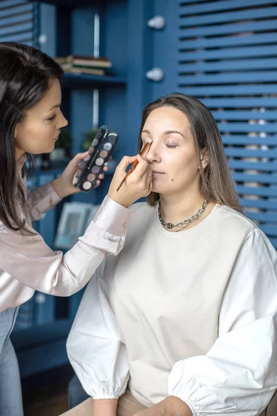 Profissional artista de maquiagem feminina aplicando cosméticos no modelo de uso do rosto escova trabalhando no salão de beleza — Fotografia de Stock