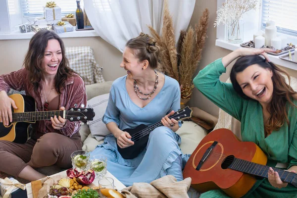 Freundinnen, die Gitarre spielen und ein Lied singen, haben Spaß bei einer Polterparty im Hippie-Bohemien-Stil — Stockfoto