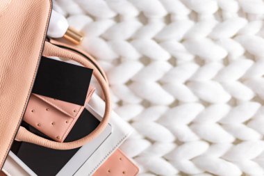 Beyaz örgü ekose üzerine uzanan kadın çantasının üst görünüm düzenleme organizasyonu