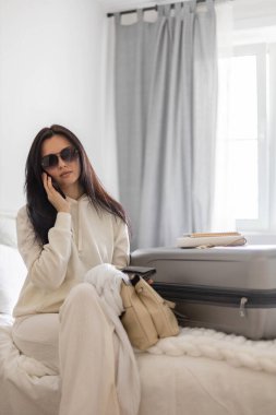 Gülümseyen kadın konuşması ayrılmadan önce akıllı telefon kullanın. Seyahate ya da iş seyahatine hazırlanırken.