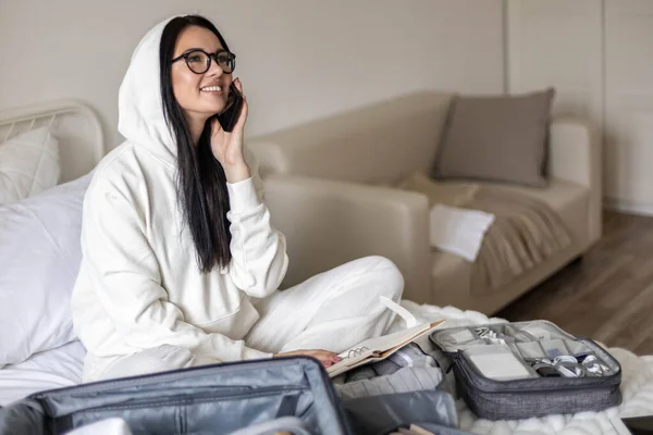 Lachende vrouw praten gebruik smartphone voor het verlaten van de voorbereiding op reizen vakantie of zakenreis — Stockfoto