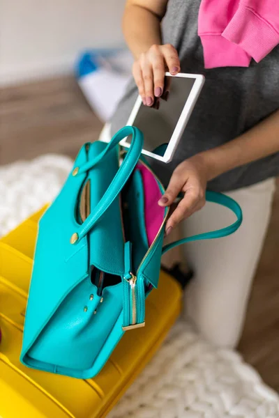 Руки жінки готові подорожі покласти планшетний ПК в сумку упаковки багажу в спальні — стокове фото