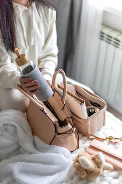 Gros plan mains féminines mettant bouteille d'eau réutilisable dans le sac à main se préparer avant de quitter — Photo