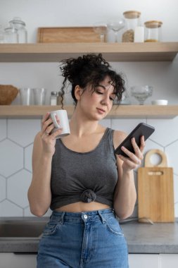 Neşeli esmer kadın internette sohbet ediyor. Akıllı telefon kullanıyor. Kafede kahve molası veriyor.