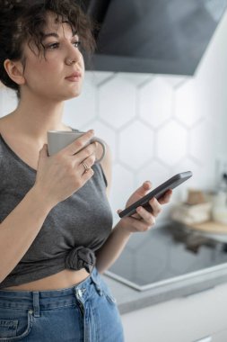 Neşeli esmer kadın internette sohbet ediyor. Akıllı telefon kullanıyor. Kafede kahve molası veriyor.
