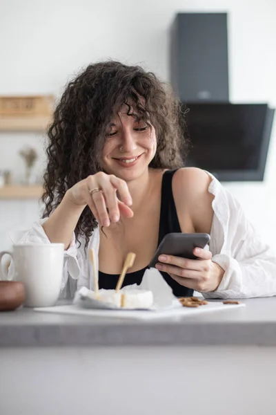 Junge Hausfrauen schreiben SMS und kommunizieren soziale Netzwerke in der weißen nordischen Küche — Stockfoto