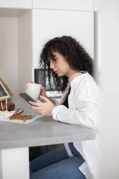 Alegre morena mujer charlando navegar por internet uso de teléfono inteligente disfrutando de un descanso de café en la cafetería — Foto de Stock