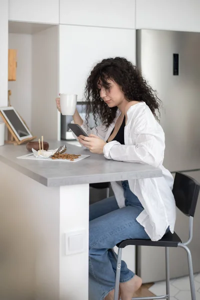 Joyful brunette vrouw chatten surfen internet gebruik smartphone genieten koffiepauze in cafe — Stockfoto