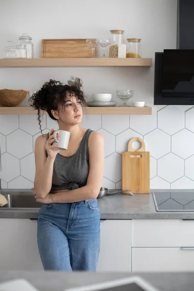 Przyjemny dom kobieta relaks w nowoczesnej kuchni rozmowy używać smartphone biały kuchnia wnętrze — Zdjęcie stockowe