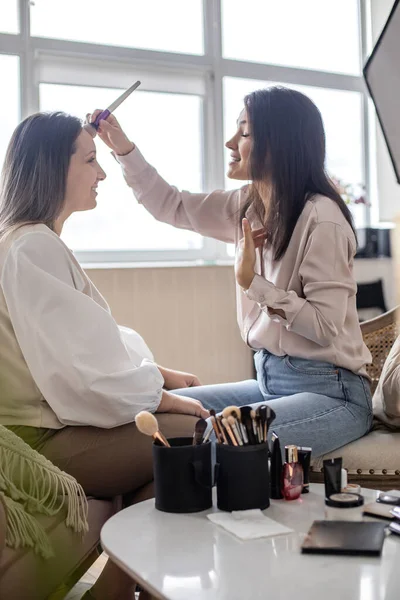 美容室で働くモデルフェイス使用ブラシに化粧品を適用するプロの女性化粧アーティスト — ストック写真
