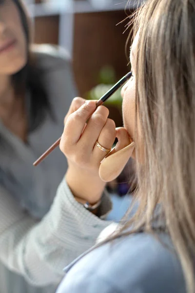 Profissional artista de maquiagem feminina aplicando cosméticos no modelo de uso do rosto escova trabalhando no salão de beleza — Fotografia de Stock