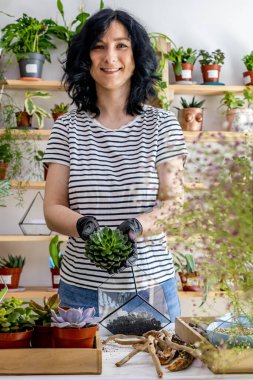 Çiçekçi kadın nakli cam floraryuma süslemeli botanik sanatı kompozisyonu ile sulandırılmış.