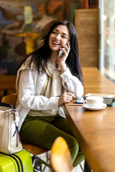 Mujer feliz sentado en la cafetería esperando vuelo de salida en la terminal del aeropuerto hablando uso de teléfono inteligente — Foto de Stock